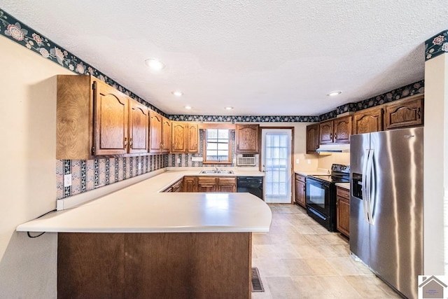 kitchen with kitchen peninsula, a textured ceiling, sink, and black appliances