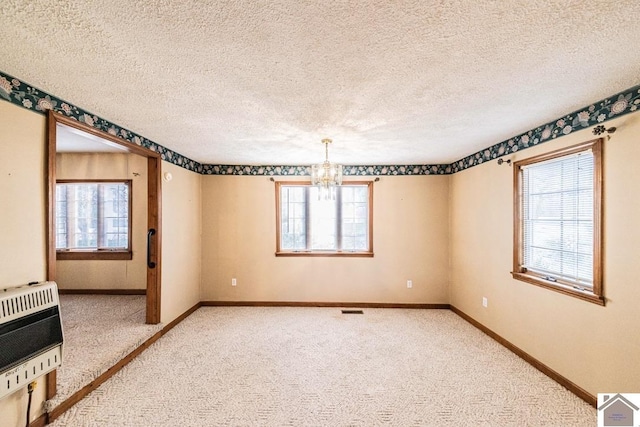 spare room with heating unit, a wealth of natural light, and an inviting chandelier