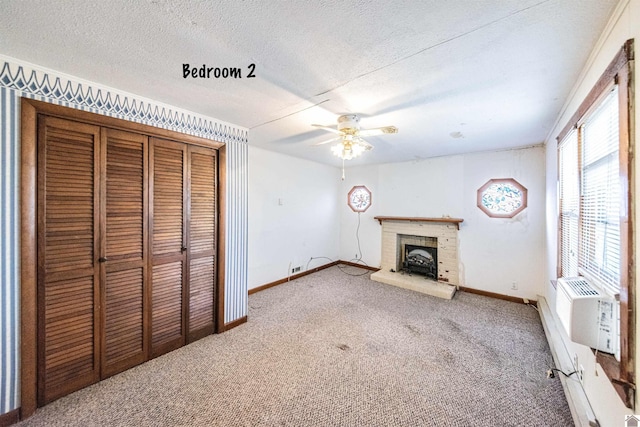 unfurnished living room featuring a textured ceiling, carpet floors, a brick fireplace, and ceiling fan