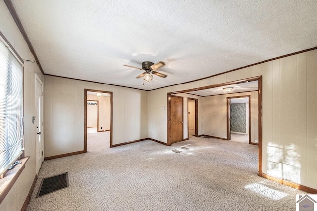 carpeted empty room with ceiling fan, a textured ceiling, and ornamental molding