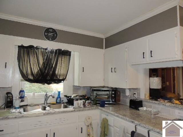 kitchen featuring light stone countertops, white cabinetry, sink, and ornamental molding