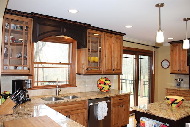 kitchen featuring light stone counters, stainless steel dishwasher, crown molding, sink, and hanging light fixtures