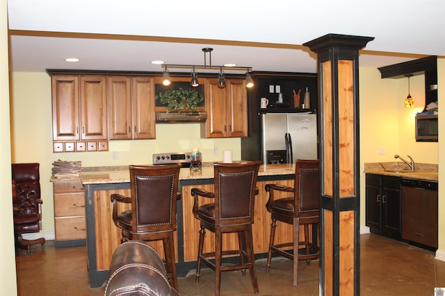 kitchen with sink, appliances with stainless steel finishes, decorative light fixtures, light stone counters, and decorative columns