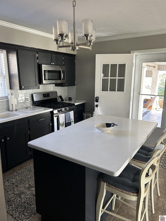 kitchen featuring pendant lighting, a center island, dark tile patterned floors, and stainless steel appliances