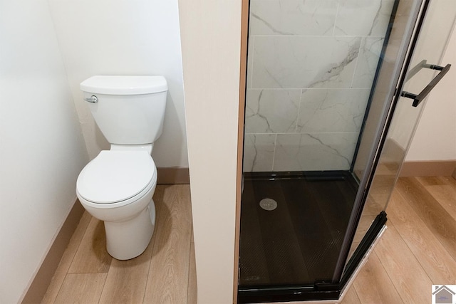 bathroom featuring tiled shower, hardwood / wood-style flooring, and toilet