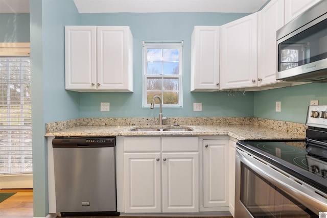 kitchen featuring light stone countertops, stainless steel appliances, white cabinetry, and sink