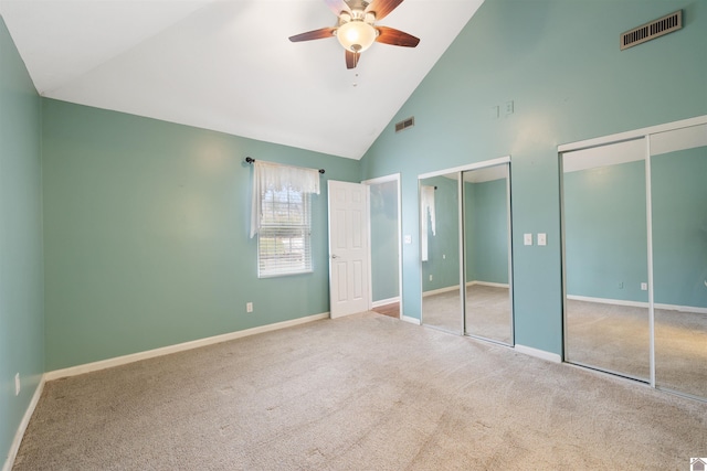 unfurnished bedroom with carpet flooring, two closets, high vaulted ceiling, and ceiling fan