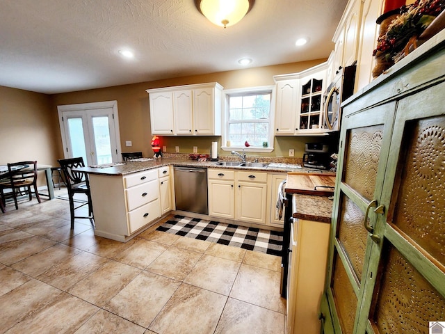 kitchen with french doors, white cabinets, sink, kitchen peninsula, and stainless steel appliances