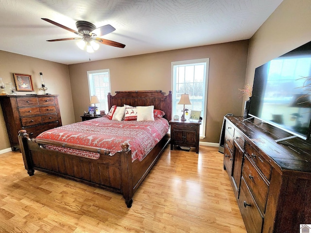 bedroom with multiple windows, ceiling fan, and light hardwood / wood-style floors