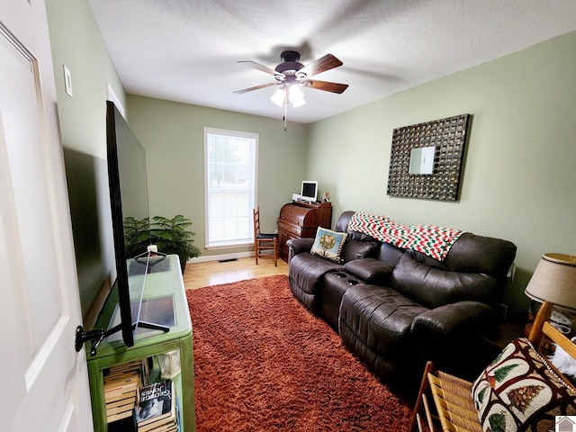 living room featuring ceiling fan, a textured ceiling, and hardwood / wood-style flooring