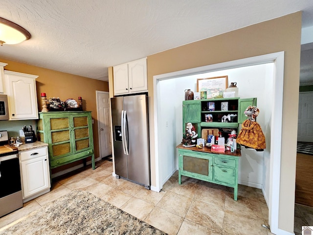 kitchen featuring light tile patterned flooring, white cabinets, stainless steel appliances, and a textured ceiling