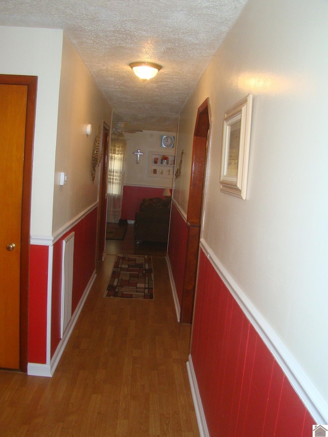 hallway with a textured ceiling and hardwood / wood-style flooring