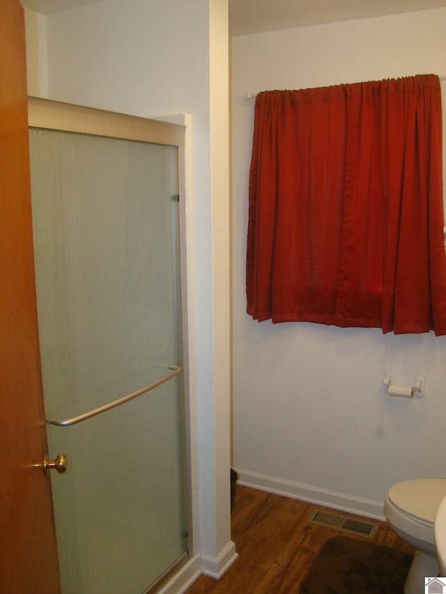 bathroom featuring hardwood / wood-style floors, toilet, and walk in shower