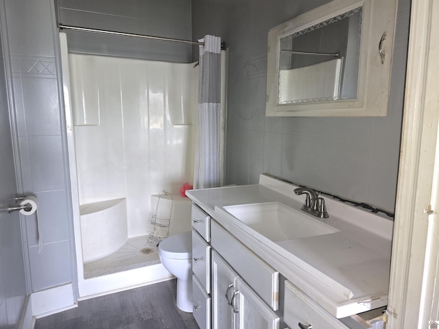 bathroom with hardwood / wood-style floors, vanity, toilet, and curtained shower