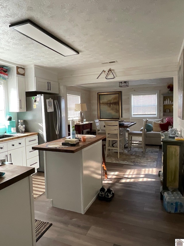 kitchen with plenty of natural light, wood-type flooring, white cabinetry, and a textured ceiling