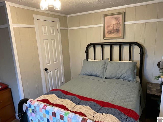 bedroom featuring crown molding, a textured ceiling, and wooden walls