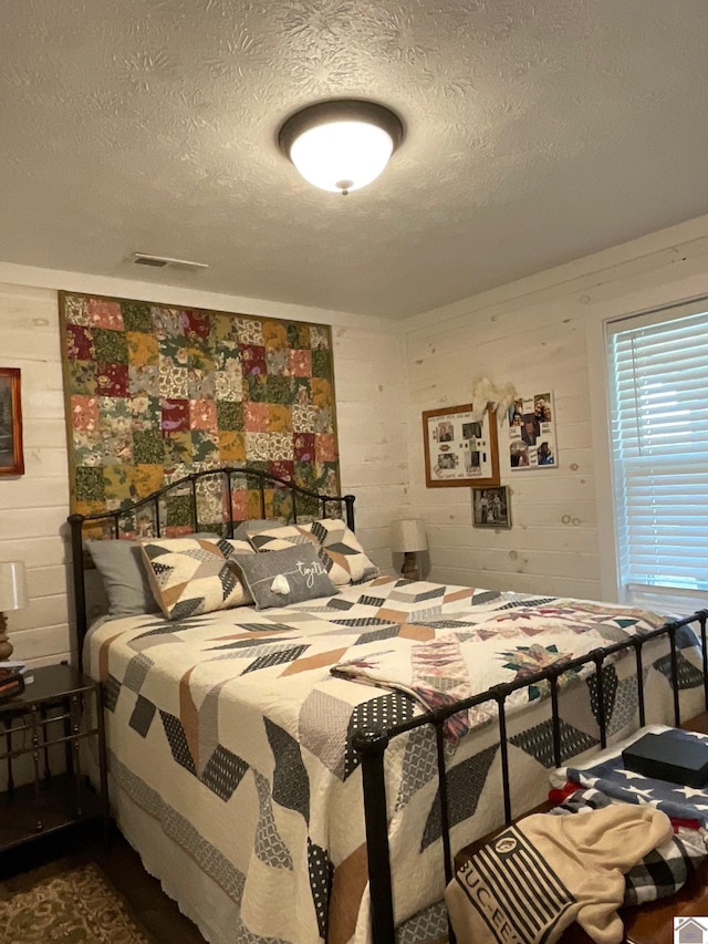 bedroom featuring wood walls and a textured ceiling