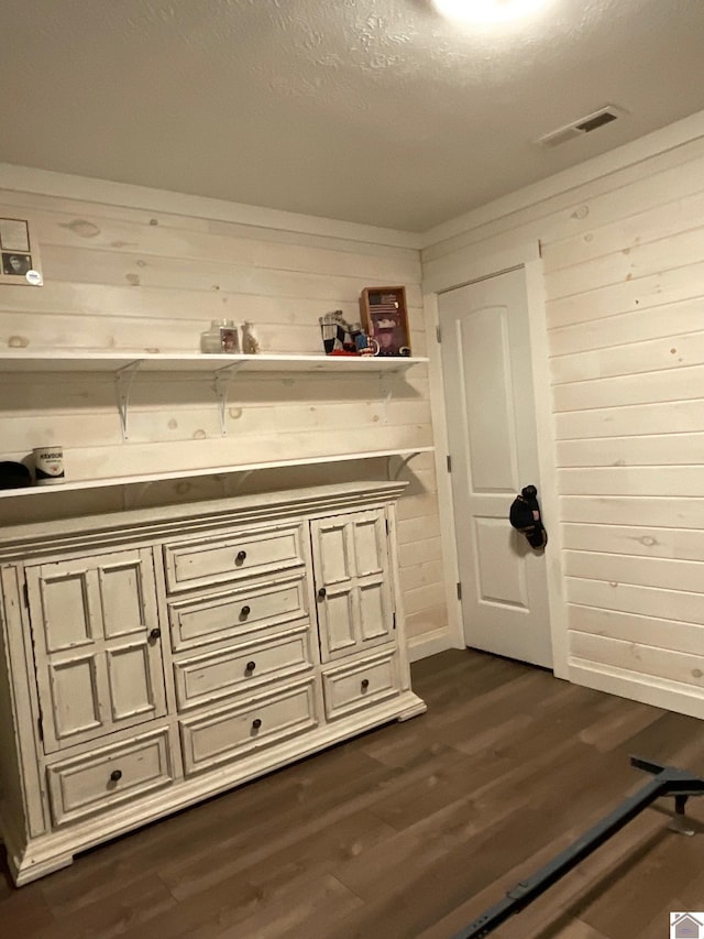 bathroom with wood walls, wood-type flooring, and a textured ceiling