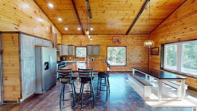 kitchen featuring beamed ceiling, stainless steel fridge with ice dispenser, decorative light fixtures, and wooden ceiling