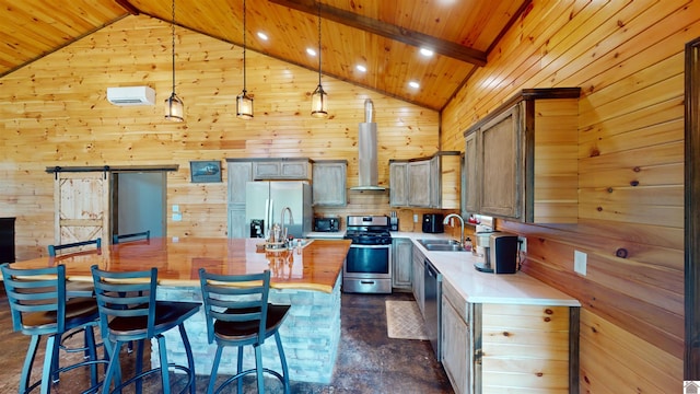 kitchen with sink, a barn door, appliances with stainless steel finishes, decorative light fixtures, and a kitchen island