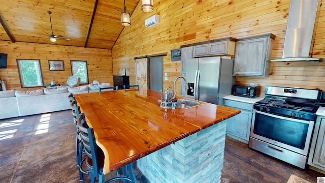 kitchen featuring wall chimney exhaust hood, stainless steel appliances, sink, a barn door, and hanging light fixtures