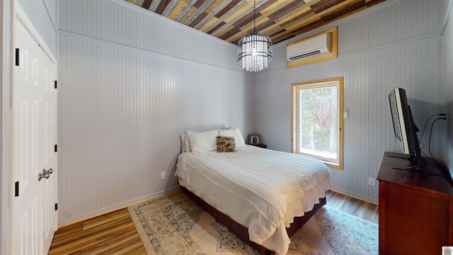 bedroom with a wall mounted air conditioner and hardwood / wood-style floors