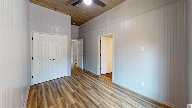 unfurnished bedroom with ceiling fan, crown molding, wood-type flooring, wooden ceiling, and a closet