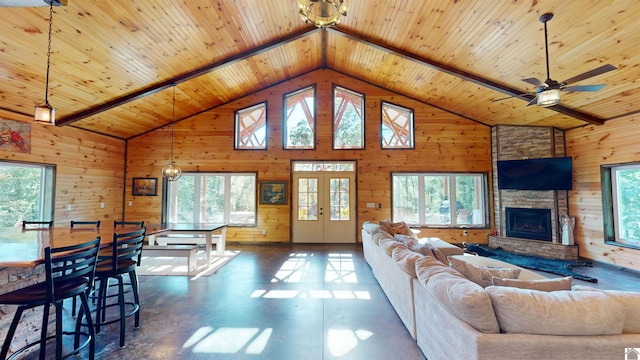 living room with beamed ceiling, a stone fireplace, and high vaulted ceiling