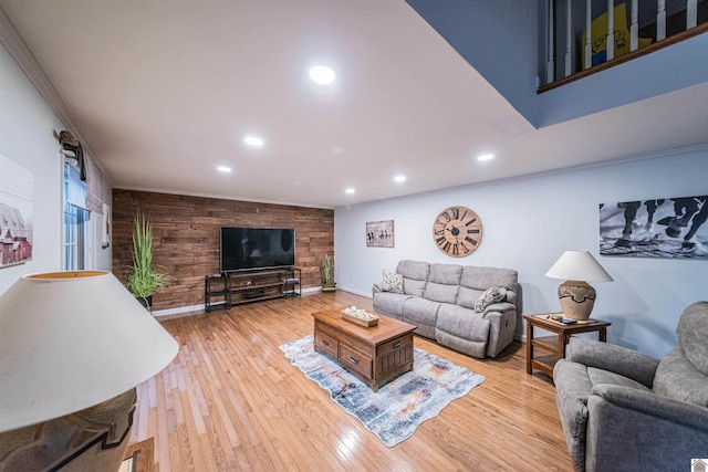 living room featuring wood walls, crown molding, and light wood-type flooring