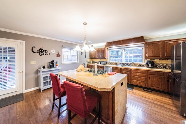 kitchen with backsplash, ornamental molding, a kitchen island, a breakfast bar area, and stainless steel appliances