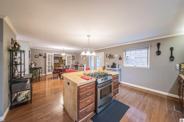 kitchen featuring stainless steel gas stove, a kitchen island, crown molding, and an inviting chandelier