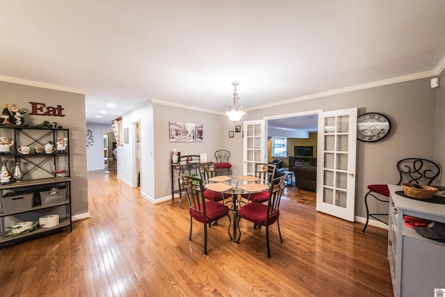 dining space featuring french doors, hardwood / wood-style flooring, crown molding, and a notable chandelier