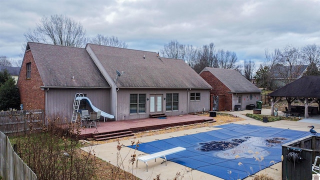 view of swimming pool featuring french doors, a wooden deck, a gazebo, a diving board, and a water slide