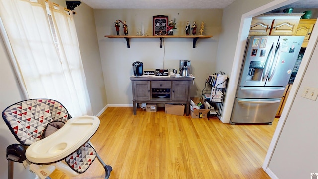 kitchen featuring wood-type flooring, stainless steel fridge with ice dispenser, and a textured ceiling