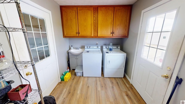 washroom featuring cabinets, light hardwood / wood-style floors, washer and dryer, and sink