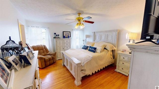 bedroom with a textured ceiling, light hardwood / wood-style floors, and ceiling fan