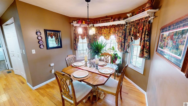 dining area with light hardwood / wood-style flooring and an inviting chandelier