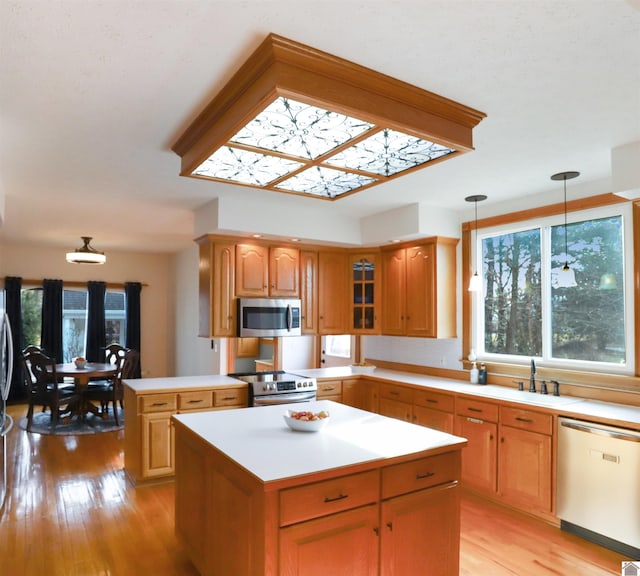 kitchen featuring appliances with stainless steel finishes, light wood-type flooring, a kitchen island, and pendant lighting