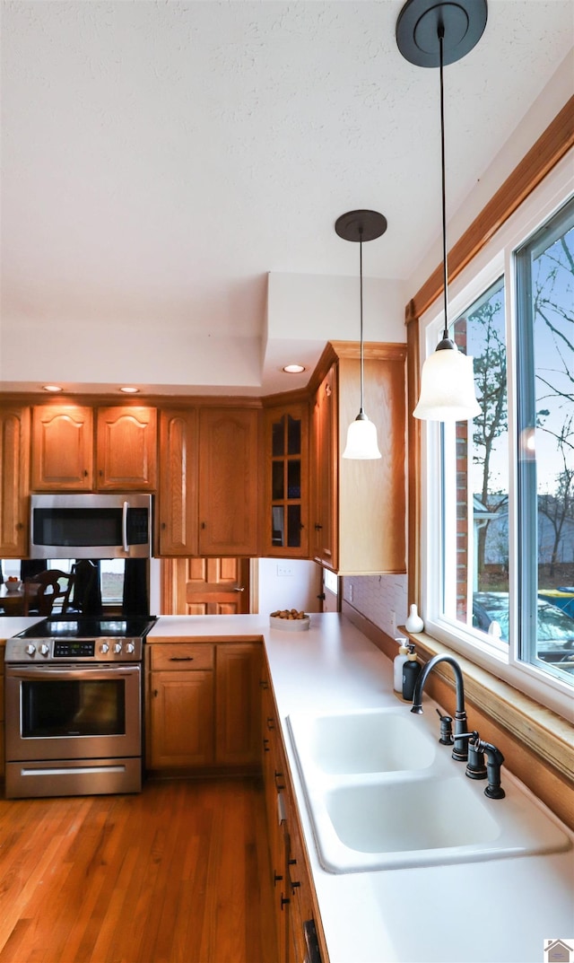 kitchen featuring dark wood-type flooring, pendant lighting, stainless steel appliances, and sink