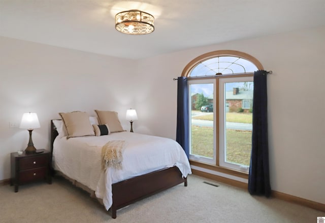 bedroom featuring multiple windows and light colored carpet