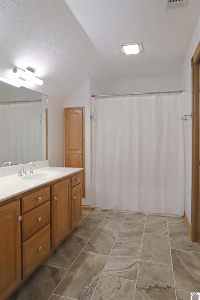 bathroom featuring vanity, lofted ceiling, and a textured ceiling