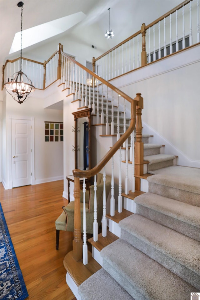 stairway featuring a chandelier, wood-type flooring, and a high ceiling