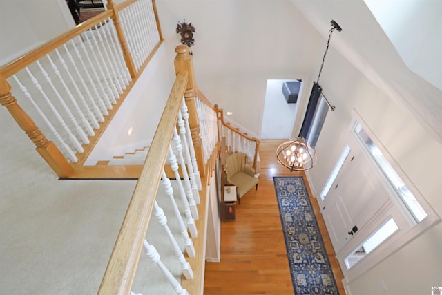 stairs with hardwood / wood-style flooring, a notable chandelier, and a high ceiling