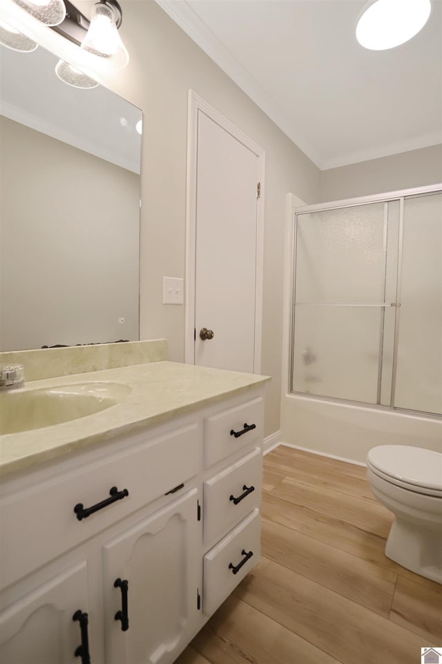 full bathroom with toilet, enclosed tub / shower combo, hardwood / wood-style flooring, ornamental molding, and vanity