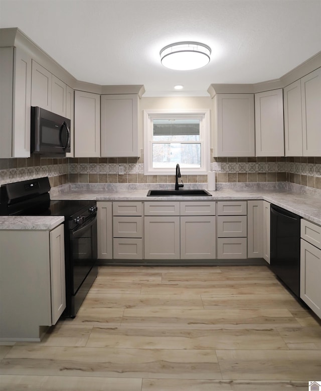 kitchen featuring gray cabinets, sink, black appliances, and tasteful backsplash