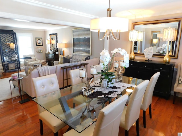 dining area with wood-type flooring, ornamental molding, and a notable chandelier