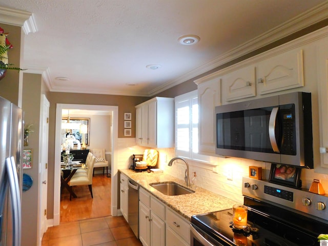 kitchen featuring ornamental molding, stainless steel appliances, sink, light tile patterned floors, and white cabinets