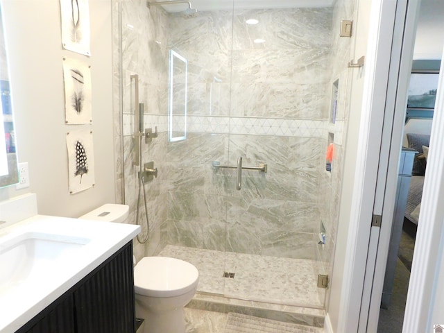 bathroom with a shower with door, vanity, and toilet