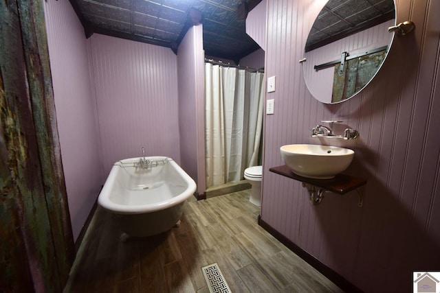 bathroom with a shower with shower curtain, toilet, wood-type flooring, and sink