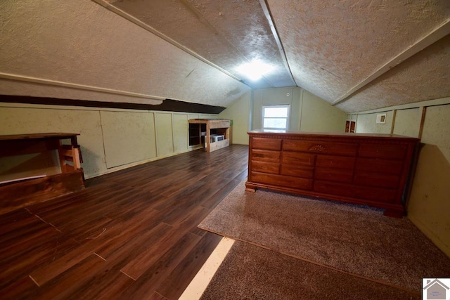 additional living space with a textured ceiling, vaulted ceiling, and dark wood-type flooring